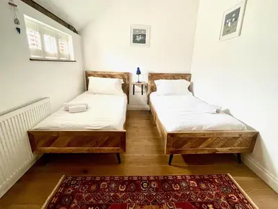 two beds in a room with a rug at Stable Cottage at Lee Wick Farm Cottages & Glamping in Clacton-on-Sea