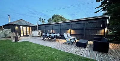 a patio with chairs and tables and a building at Stable Cottage at Lee Wick Farm Cottages & Glamping in Clacton-on-Sea