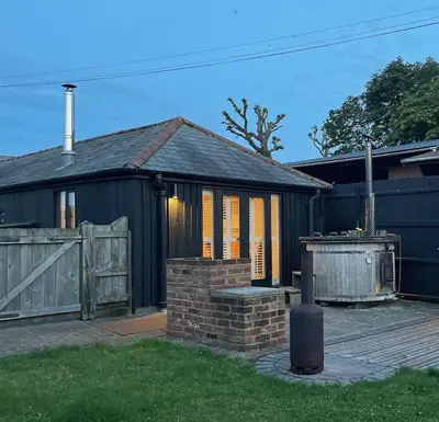 a house with a gate and a brick fireplace at Stable Cottage at Lee Wick Farm Cottages & Glamping in Clacton-on-Sea
