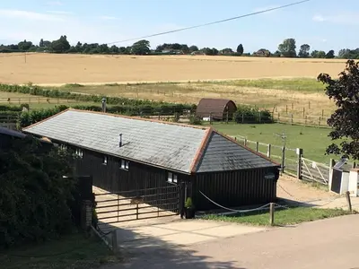 a barn with a metal roof in a field at Stable Cottage at Lee Wick Farm Cottages & Glamping in Clacton-on-Sea