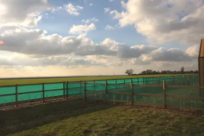 a fence next to a body of water at Lushna 3 Petite at Lee Wick Farm Cottages & Glamping in Clacton-on-Sea