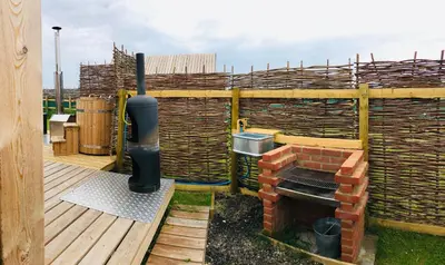 a patio with a brick oven on a deck at Lushna 6 Petite at Lee Wick Farm Cottages & Glamping in Clacton-on-Sea