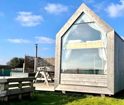a small shed with a window on a deck at Lushna 7 Petite at Lee Wick Farm Cottages & Glamping in Clacton-on-Sea