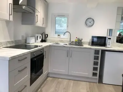 a kitchen with white cabinets and a sink and a microwave at Dolly Cottage Colchester in Mile End