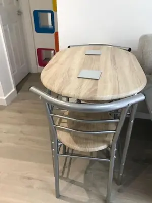 a wooden table with a chair around it at Dolly Cottage Colchester in Mile End