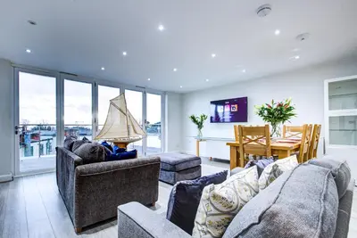 a living room with couches and a dining room with a table at leigh Penthouse Apartment in Leigh-on-Sea