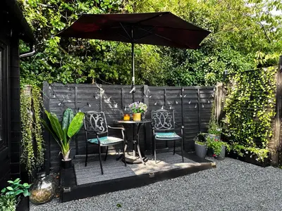 a table with two chairs and an umbrella at The Cabin Near Stansted Airport in Little Hallingbury
