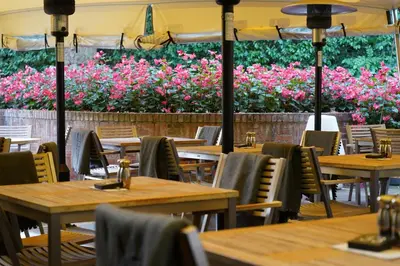 an empty restaurant with wooden tables and pink flowers at Milsoms in Dedham