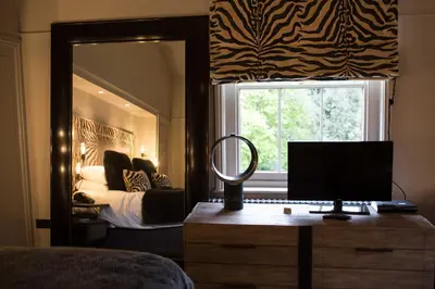 a bedroom with a bed and a mirror and a desk with a monitor at Milsoms in Dedham