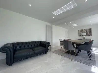 a living room with a black couch and a table at Large Countryside House Swim Pool Jacuzzi Sleeps 10 guest in Ware
