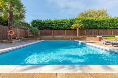 a swimming pool with blue water in a backyard at Large Countryside House Swim Pool Jacuzzi Sleeps 10 guest in Ware
