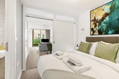 a white bedroom with a large white bed with green pillows at Tailored Stays - Central Cambridge, River Walk Apartments in Cambridge
