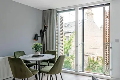 a dining room with a table and chairs and a large window at Tailored Stays - Central Cambridge, River Walk Apartments in Cambridge