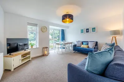 a living room with a blue couch and a tv at Shore House - Walton in Walton-on-the-Naze