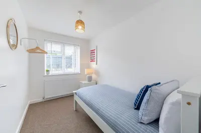 a white bedroom with a bed and a window at Shore House - Walton in Walton-on-the-Naze