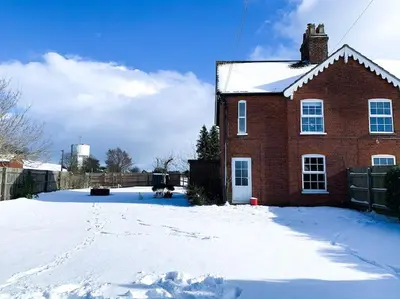 a red brick house with snow on the ground at Victorian quirky farm cottage next to forest & close to beach in Woodbridge