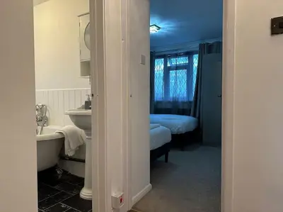 a bathroom with a sink and a tub and a bed at Spacious 4 bedroom house in Billericay