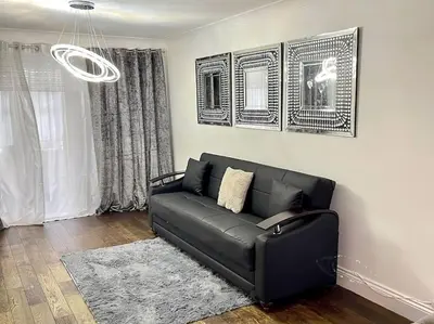 a black couch in a living room with a window at Spacious 4 bedroom house in Billericay