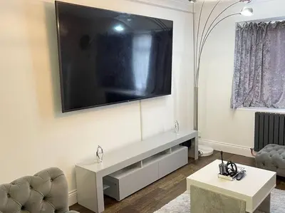 a living room with a large television on the wall at Spacious 4 bedroom house in Billericay
