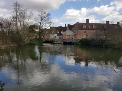 a river in a town with a bridge and buildings at Landscape, New Eco Lodge Flatford Mill in East Bergholt