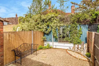 a metal bench sitting in front of a fence at Curlew Cottage Woodbridge Suffolk Cosy Victorian cottage for couple and dog in Woodbridge