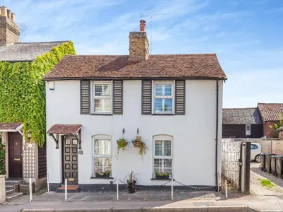 a white house with black shutters at Cutters Cottage in Roydon