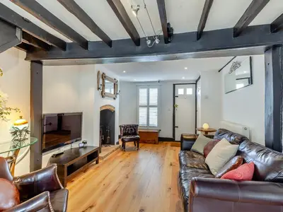 a living room with a leather couch and a television at Cutters Cottage in Roydon