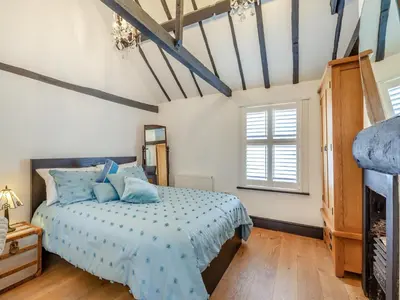 a bedroom with a blue bed and a fireplace at Cutters Cottage in Roydon
