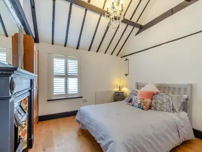 a bedroom with a bed and a chandelier at Cutters Cottage in Roydon