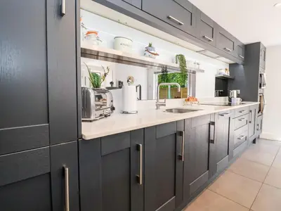 a kitchen with black cabinets and a sink at Cavan Cottage in Saxmundham