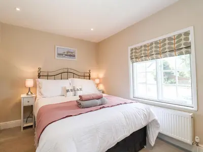 a bedroom with a large bed and a window at Cavan Cottage in Saxmundham