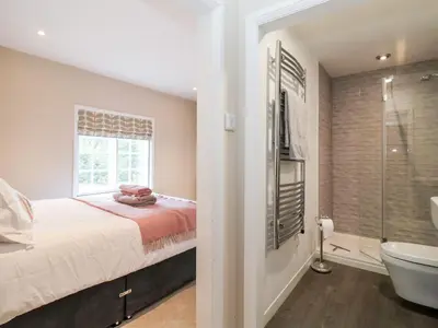 a bedroom with a bed and a bathroom with a tub at Cavan Cottage in Saxmundham