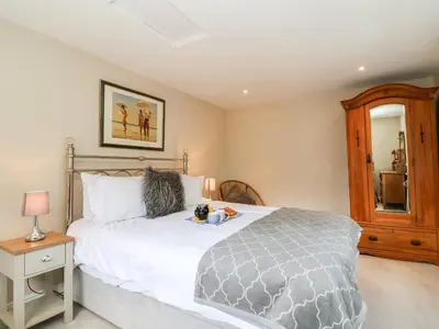 a bedroom with a large bed and a mirror at Cavan Cottage in Saxmundham