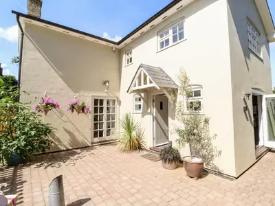 a large white house with a brick courtyard at Cavan Cottage in Saxmundham