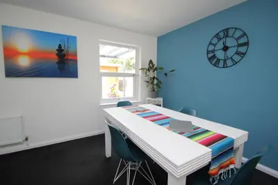 a room with a white table with chairs and a clock at The Zen Den in Southend-on-Sea