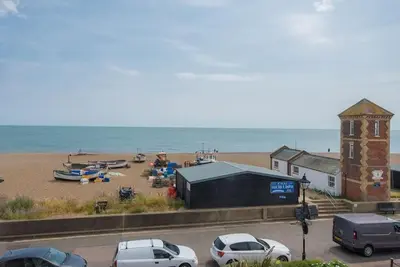 a beach with parked cars and a building and the ocean at Trehafod, Aldeburgh in Aldeburgh