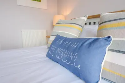 a bed with a blue pillow that says not in the marrying at Trehafod, Aldeburgh in Aldeburgh