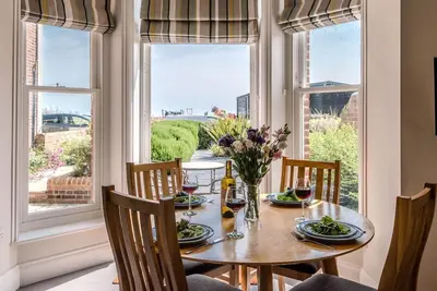 a dining room with a table and chairs and a window at Trehafod, Aldeburgh in Aldeburgh