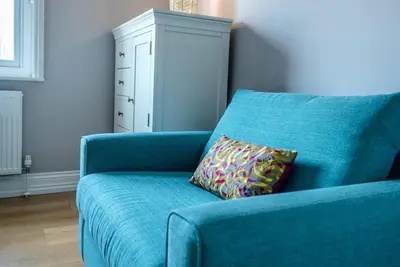 a blue couch with a pillow next to a white cabinet at Lyndhurst, Aldeburgh in Aldeburgh
