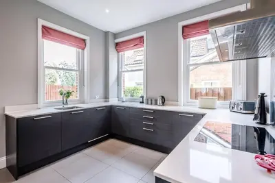 a kitchen with black cabinets and two windows at Lyndhurst, Aldeburgh in Aldeburgh