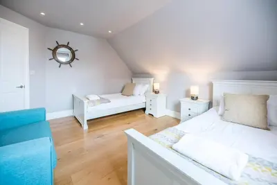 a bedroom with two beds and a mirror on the wall at Lyndhurst, Aldeburgh in Aldeburgh