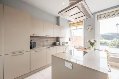 a kitchen with white cabinets and a large window at Swn-y-Don, Aldeburgh in Aldeburgh