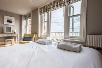 a bedroom with a large white bed with windows at Swn-y-Don, Aldeburgh in Aldeburgh