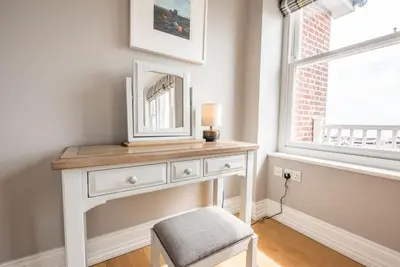 a white dresser with a mirror and a stool in a room at Swn-y-Don, Aldeburgh in Aldeburgh