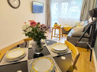 a living room with a table with plates and flowers on it at 2 Single Beds, 1 BR Apartment in Newmarket