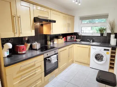 a kitchen with wooden cabinets and a washer and dryer at 2 Single Beds, 1 BR Apartment in Newmarket