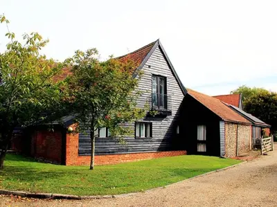 a black house with a tree in front of it at Stunning barn conversion ideal for large families in Bildeston