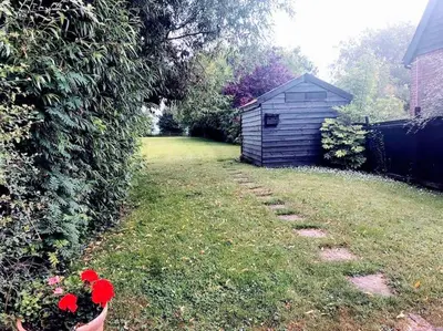 a yard with a shed and red flowers in a vase at Stunning barn conversion ideal for large families in Bildeston