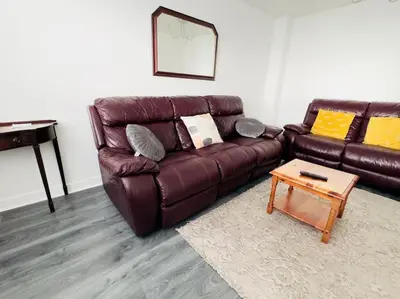 a brown leather couch in a living room with a table at Tranquil Haven: 3-BR House in Great Burstead