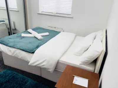 a bed with two white towels on top of it at Tranquil Haven: 3-BR House in Great Burstead